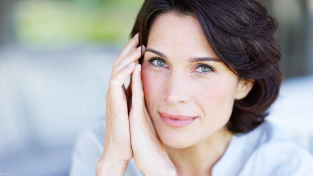 Woman looking at the camera with her hands on her face (MODEL)