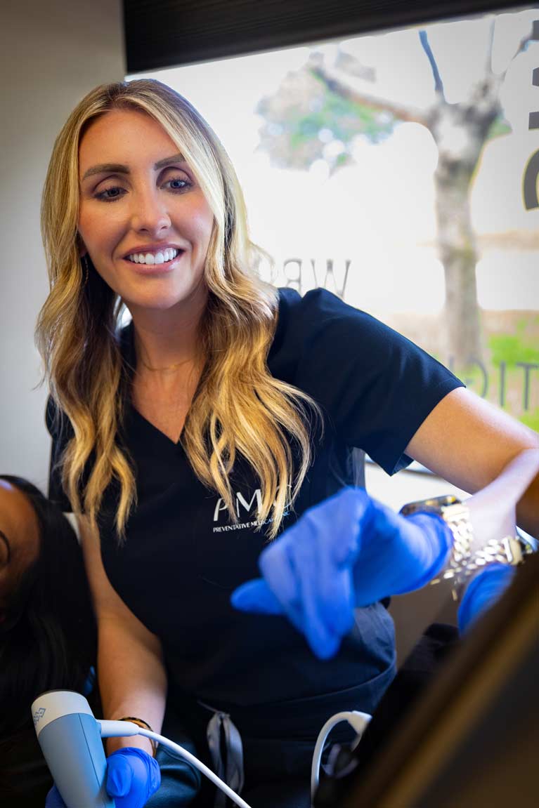 A clinician in a black uniform smiles warmly at the camera while administering an Exion treatment to a patient, emphasizing a friendly and professional healthcare environment.